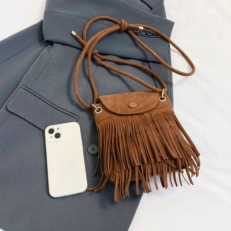 Petit sac bandoulière à franges marron à côté d'un téléphone