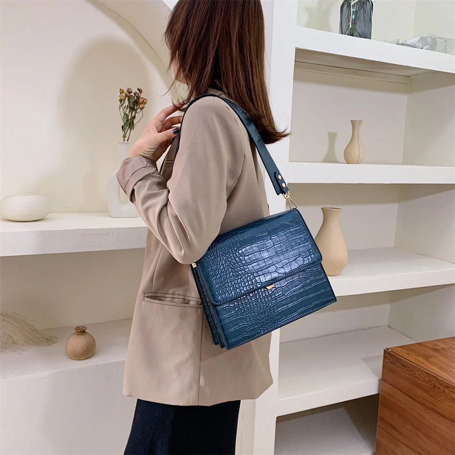 Sac bandoulière imitation croco bleu porté à l'épaule