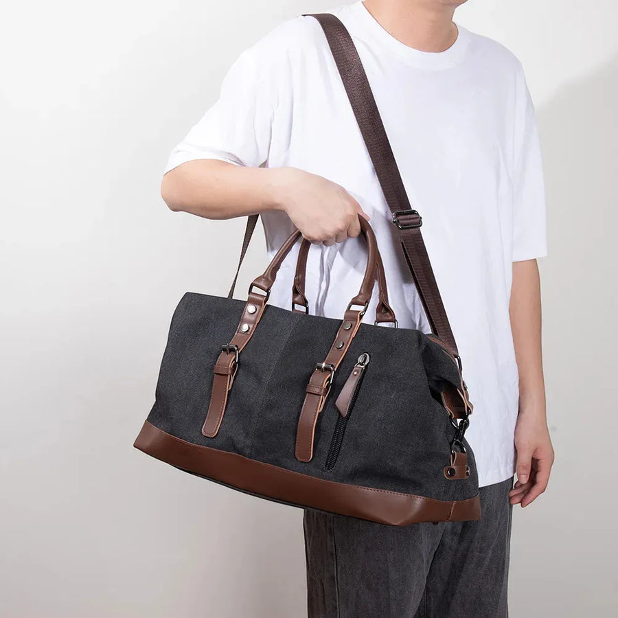Sac de voyage en toile homme noir porté en bandoulière