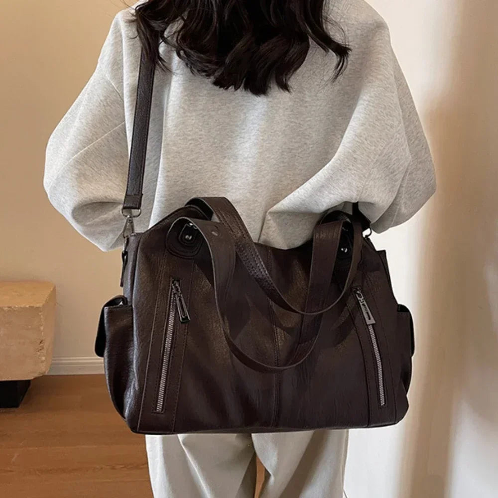 Grand sac à main marron foncé porté à l’épaule avec une tenue claire