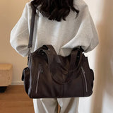 Grand sac à main marron foncé porté à l’épaule avec une tenue claire