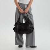 Grand sac à main noir porté à la main avec un pantalon gris