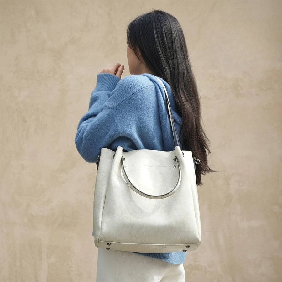 Sac cabas femme en cuir véritable blanc cassé porté à l’épaule sur fond beige