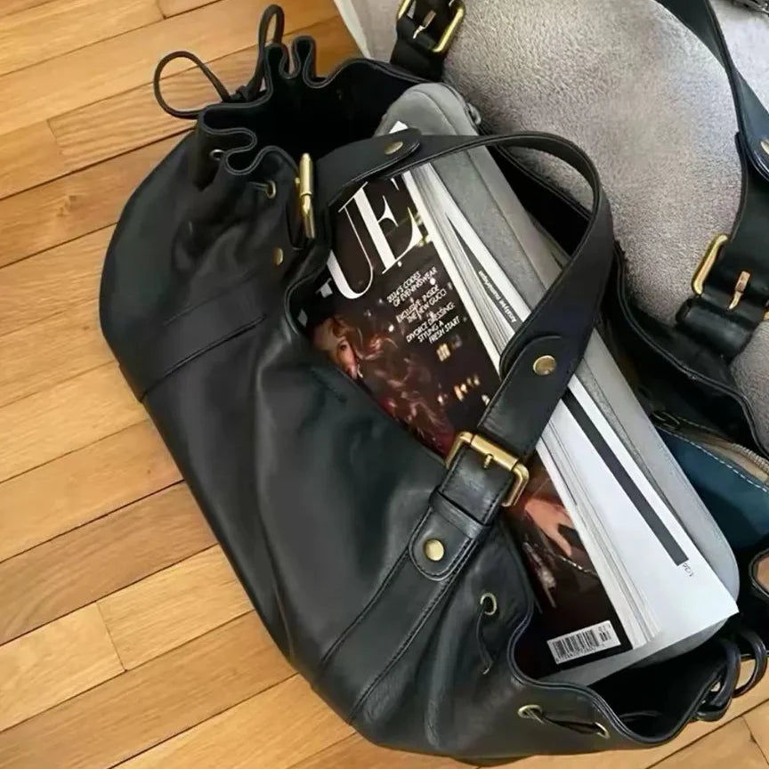 Sac à main vintage noir ouvert avec plusieurs objets à l'intérieur