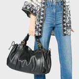 Sac à main vintage noir porté avec un jean