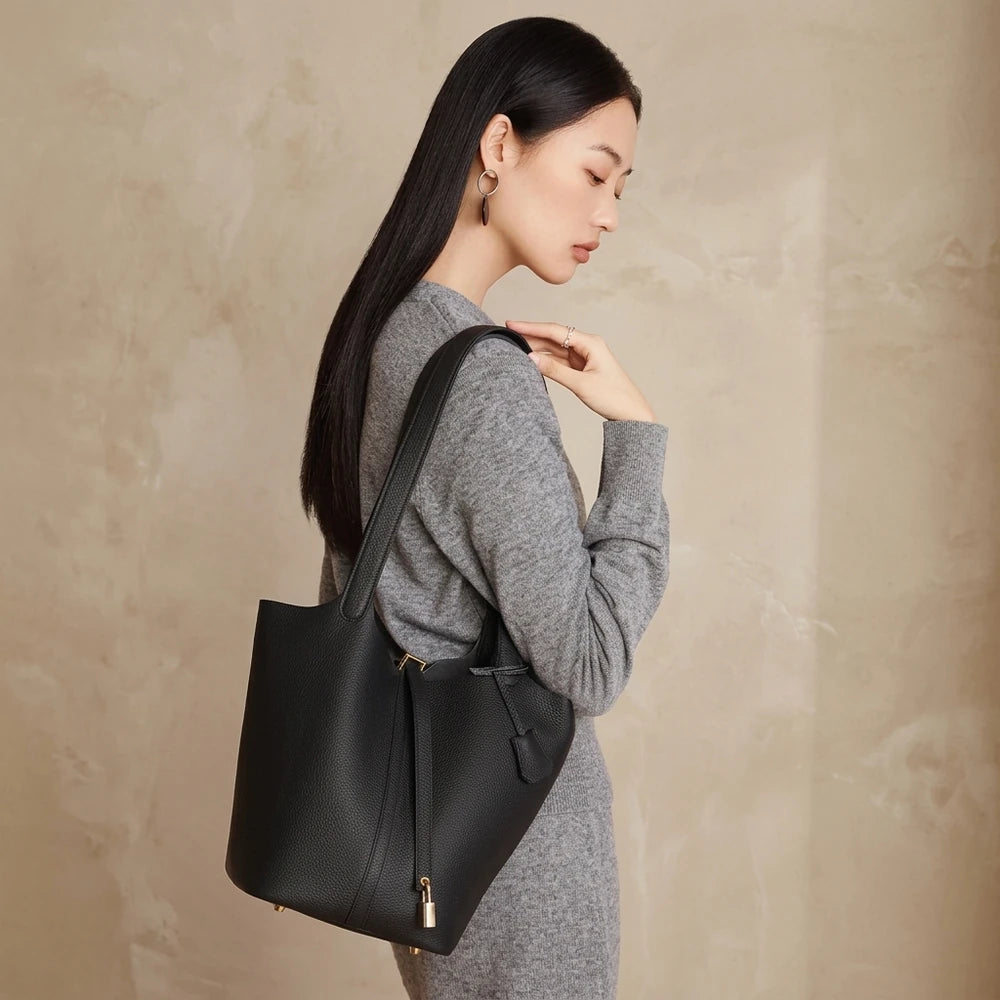 Sac seau femme noir en cuir véritable porté à l’épaule, vue de profil