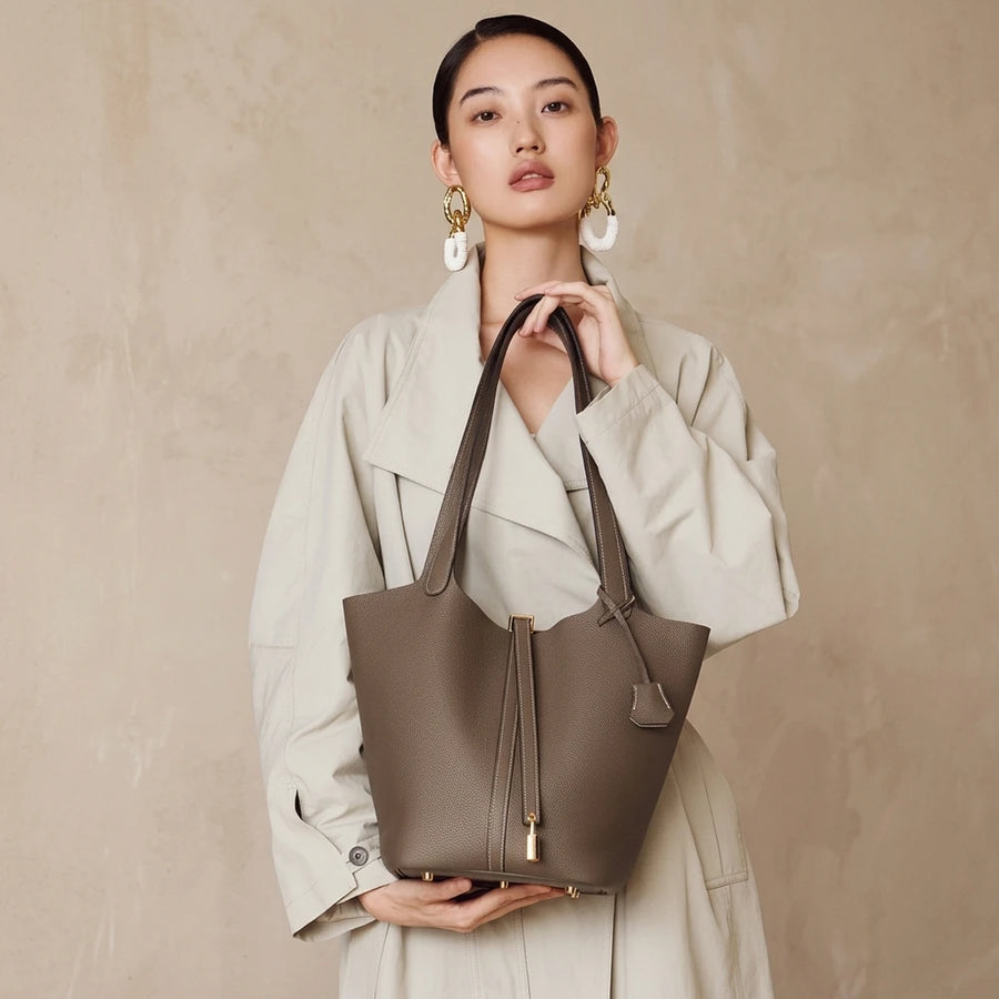 Sac seau femme en cuir véritable porté de face sur fond beige