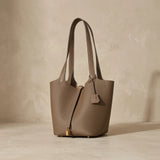 Sac seau femme en cuir véritable posé sur fond studio beige