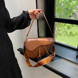 sac à main selle de cheval en cuir marron porté à la main