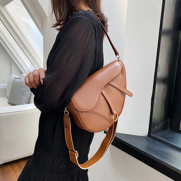 sac à main selle de cheval en cuir marron porté épaule